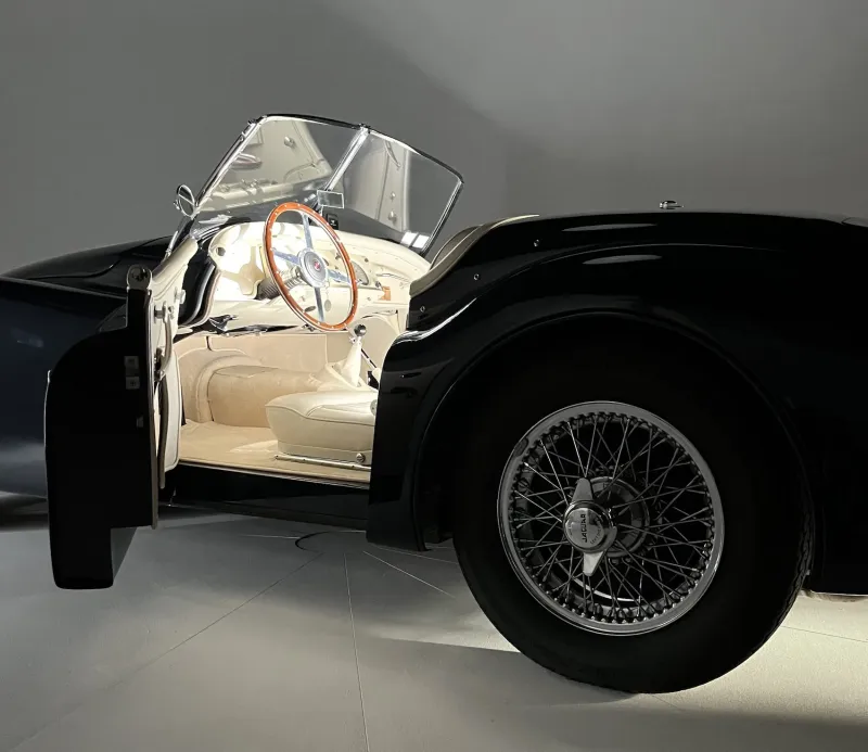 Shooting automobile : détail d'un cabriolet ancien noir, roue à rayons et intérieur crème