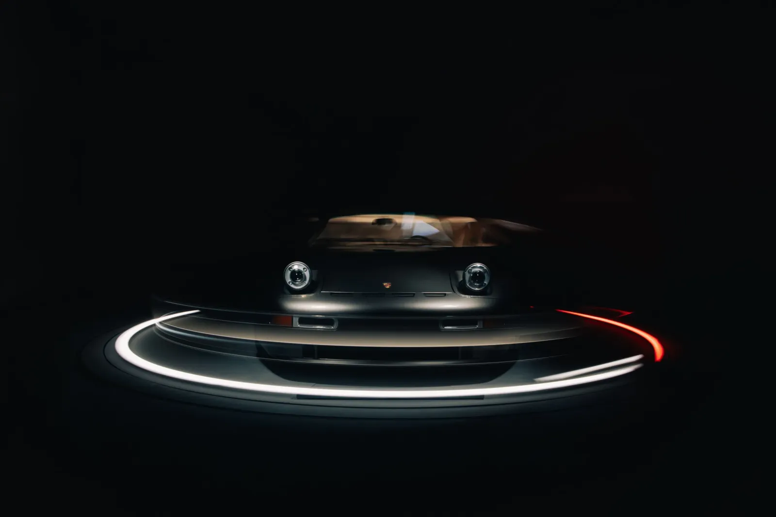 Face avant d'une Porsche Nardone sur le plateau tournant, pose longue : traînées de lumière blanche et rouge dans le noir